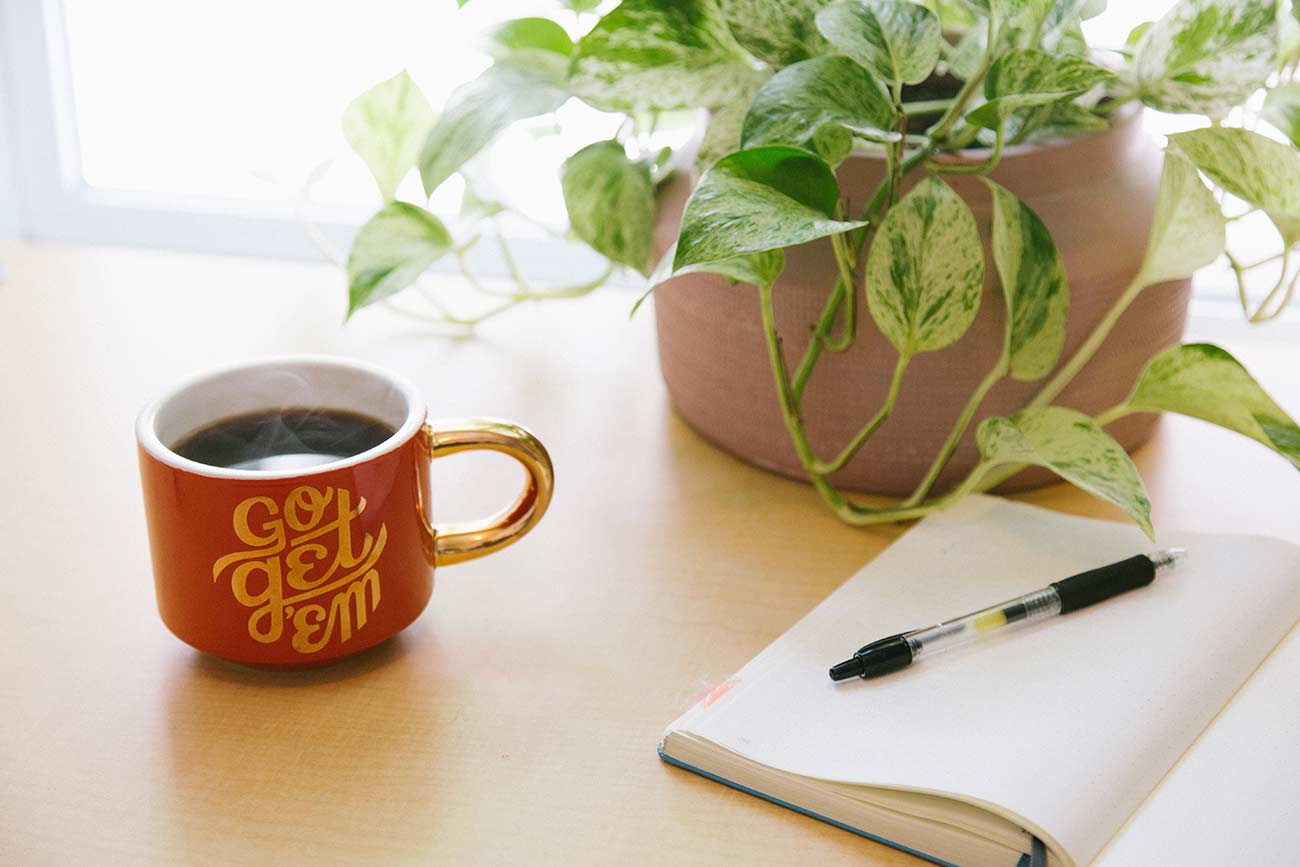 Coffee cup and copywriting notepad on bright desk